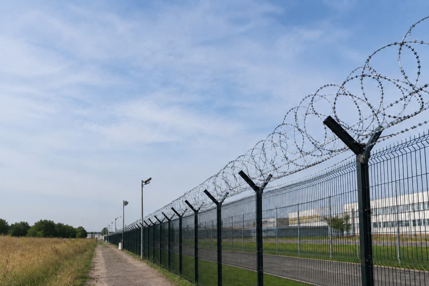 Security fence with razor wire under a blue sky